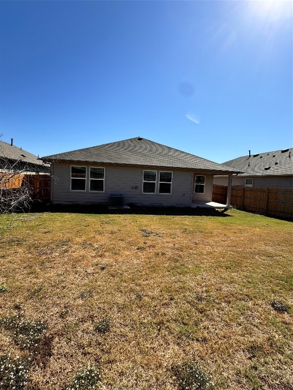 back of property with a lawn and central AC