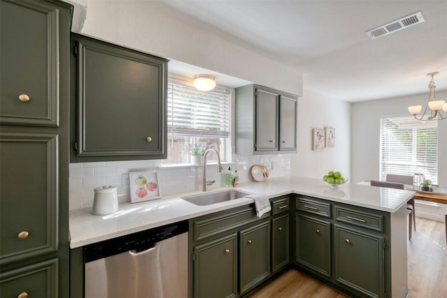 kitchen featuring dishwasher, sink, decorative light fixtures, light hardwood / wood-style floors, and kitchen peninsula