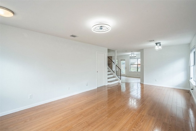 spare room with an inviting chandelier and light wood-type flooring