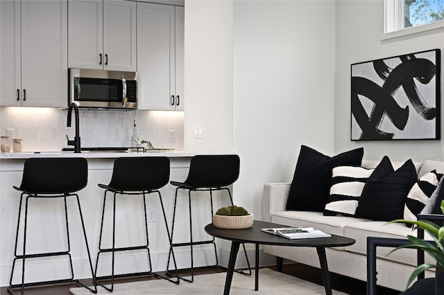 kitchen featuring white cabinetry, light hardwood / wood-style floors, sink, and backsplash