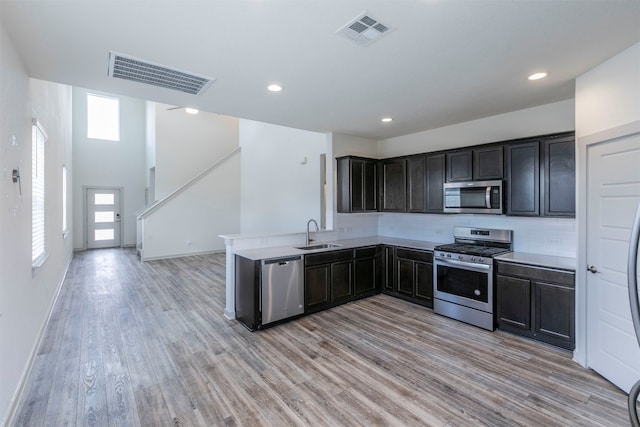 kitchen with sink, light hardwood / wood-style flooring, dark brown cabinetry, kitchen peninsula, and stainless steel appliances