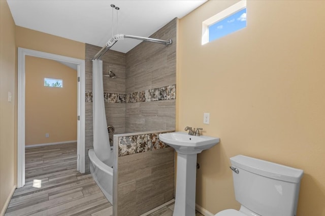 bathroom with hardwood / wood-style floors, shower / bath combo, plenty of natural light, and toilet