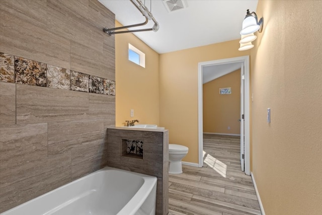 full bathroom with hardwood / wood-style flooring, sink, toilet, vaulted ceiling, and tiled shower / bath combo