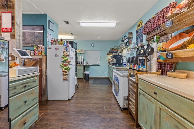 kitchen featuring dark wood-type flooring, white refrigerator, green cabinets, a textured ceiling, and washer / clothes dryer