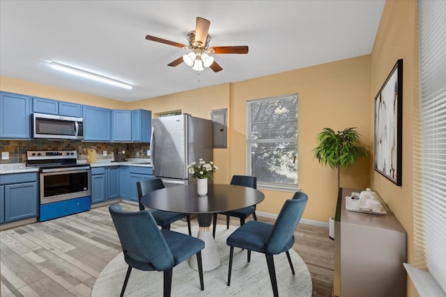 kitchen featuring light wood-type flooring, appliances with stainless steel finishes, backsplash, blue cabinets, and ceiling fan