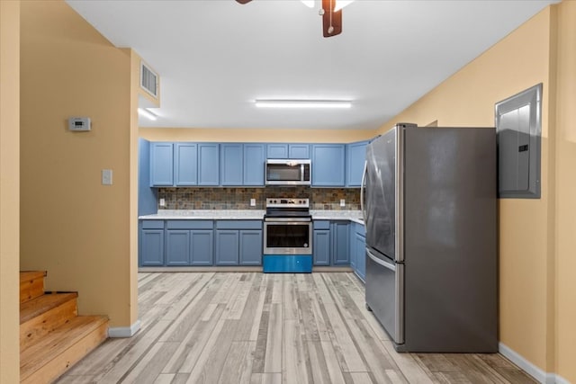 kitchen with tasteful backsplash, blue cabinetry, appliances with stainless steel finishes, and light hardwood / wood-style floors