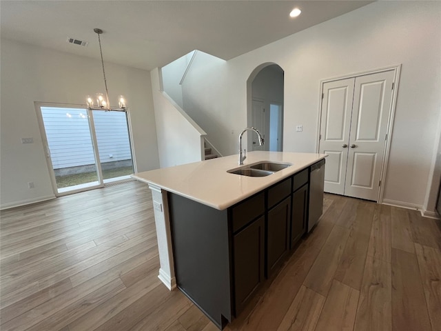 kitchen with stainless steel dishwasher, a center island with sink, sink, and light wood-type flooring