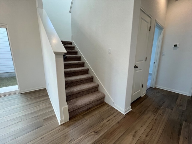 stairs featuring a wealth of natural light and hardwood / wood-style flooring