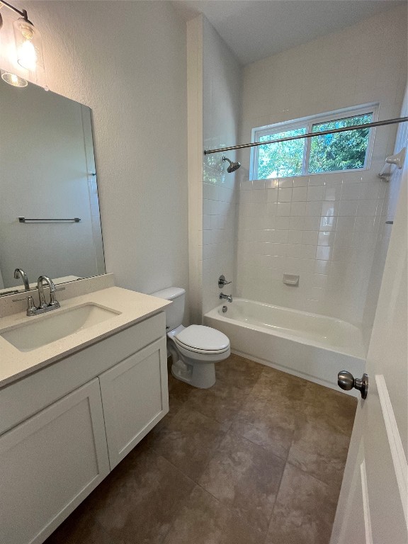 full bathroom with toilet, tiled shower / bath combo, vanity, and tile patterned flooring