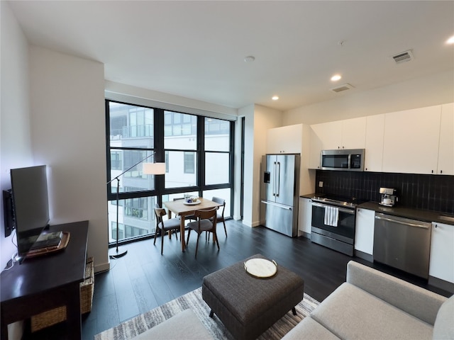 kitchen with dark hardwood / wood-style flooring, white cabinetry, backsplash, and stainless steel appliances