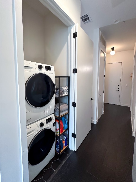 laundry room with dark wood-type flooring and stacked washer and clothes dryer