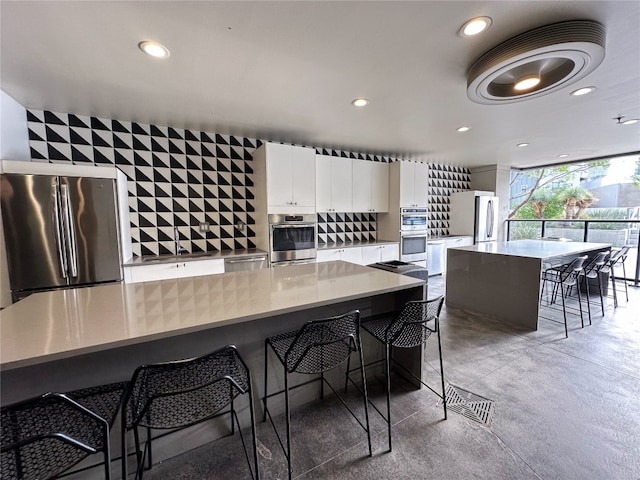 kitchen featuring white cabinetry, appliances with stainless steel finishes, a breakfast bar, and a large island