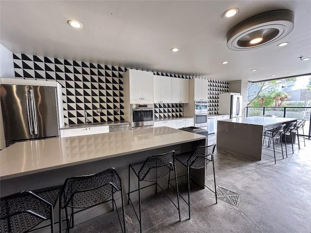 800 Embassy Dr Unit 530, Austin, TX 78702 - kitchen featuring appliances with stainless steel finishes, white cabinets, a breakfast bar, recessed lighting, and a spacious island