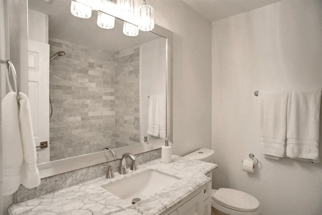 bathroom with toilet, vanity, and tiled shower