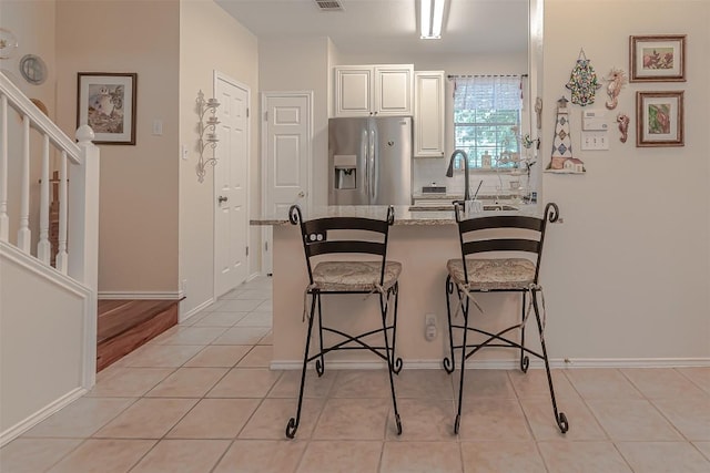 2000 Cullen Ave Unit 9, Austin, TX 78757 - kitchen with stainless steel fridge with ice dispenser, a breakfast bar area, a peninsula, white cabinets, and decorative backsplash