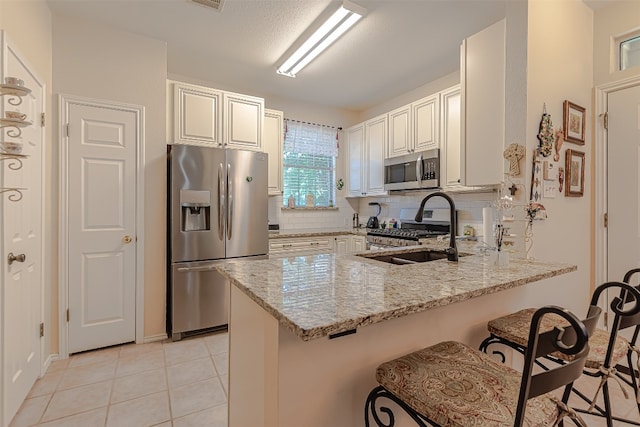 kitchen with kitchen peninsula, appliances with stainless steel finishes, tasteful backsplash, and light stone counters