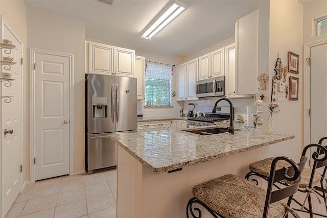 2000 Cullen Ave Unit 9, Austin, TX 78757 - kitchen featuring appliances with stainless steel finishes, a peninsula, light stone counters, a breakfast bar, and tasteful backsplash