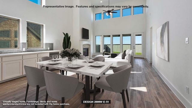 dining room featuring dark wood-type flooring, ceiling fan, and a high ceiling