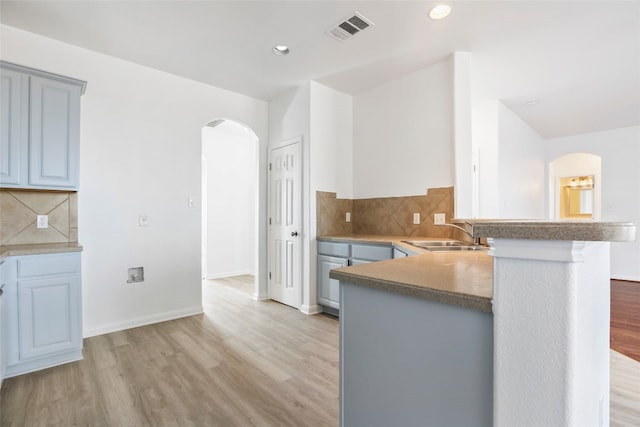 kitchen featuring light hardwood / wood-style floors, sink, kitchen peninsula, and tasteful backsplash