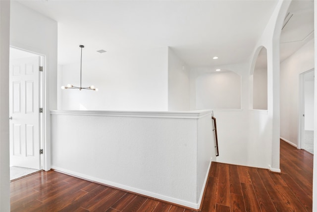 corridor featuring dark hardwood / wood-style flooring and an inviting chandelier