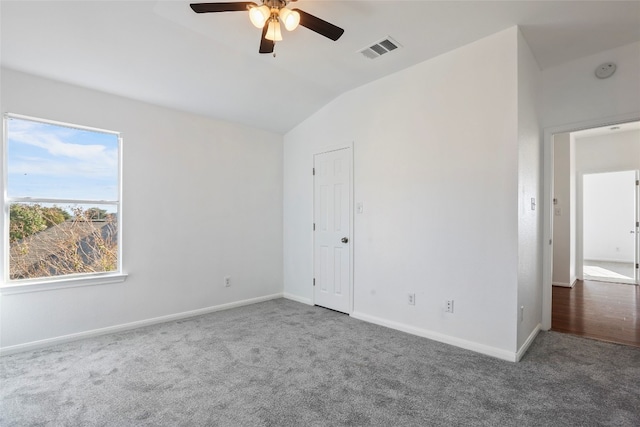 unfurnished room with vaulted ceiling, dark colored carpet, and ceiling fan