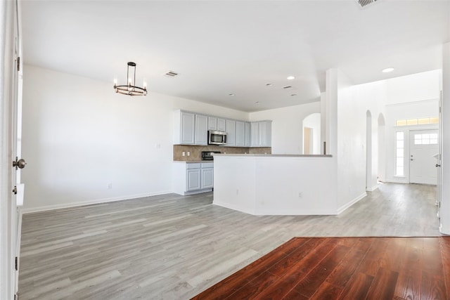 unfurnished living room with a notable chandelier and light hardwood / wood-style floors