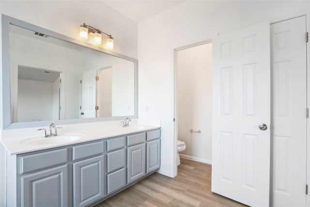 bathroom with wood-type flooring, toilet, and vanity