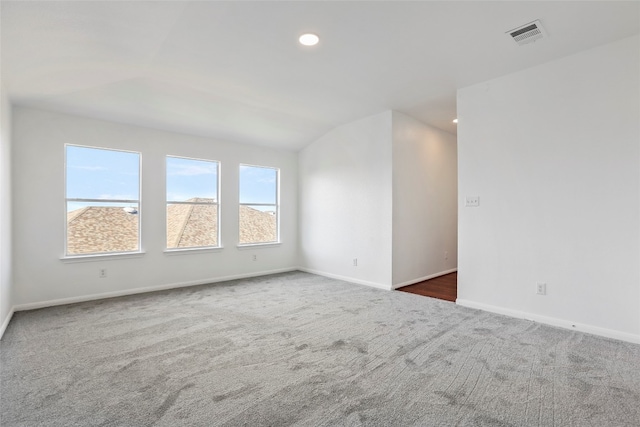 empty room featuring dark colored carpet and vaulted ceiling