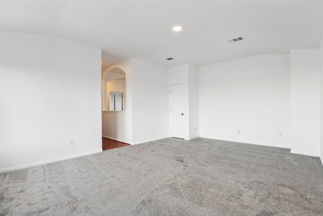 carpeted empty room with vaulted ceiling