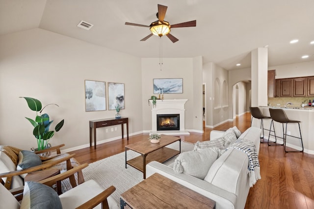 living room with hardwood / wood-style flooring, ceiling fan, and vaulted ceiling