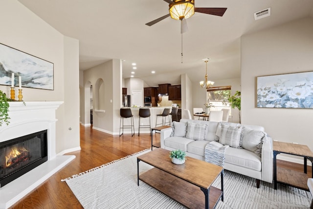 living room with wood-type flooring and ceiling fan with notable chandelier