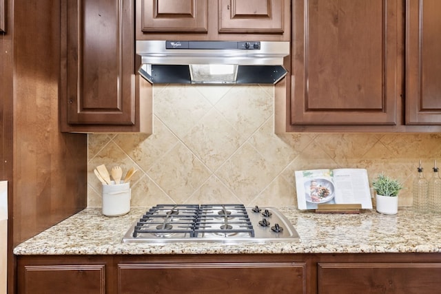 kitchen featuring stainless steel gas cooktop, decorative backsplash, and light stone counters