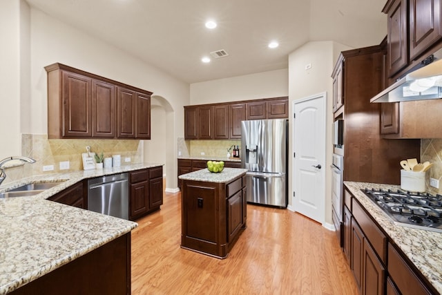 kitchen with light hardwood / wood-style flooring, sink, a kitchen island, light stone countertops, and appliances with stainless steel finishes