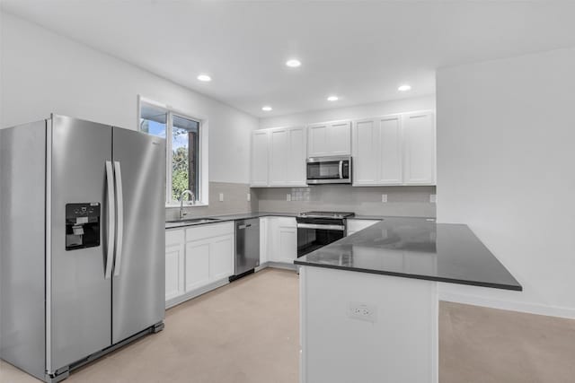 kitchen featuring white cabinetry, sink, kitchen peninsula, appliances with stainless steel finishes, and backsplash