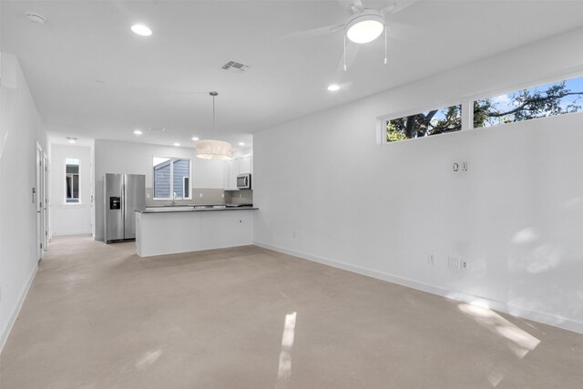 unfurnished living room featuring ceiling fan and sink