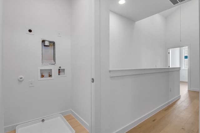 clothes washing area featuring hookup for a washing machine, light hardwood / wood-style flooring, electric dryer hookup, and gas dryer hookup