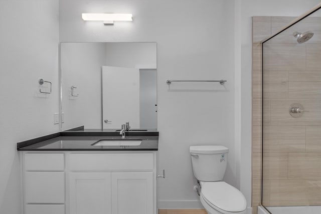 bathroom with toilet, vanity, and a shower with door