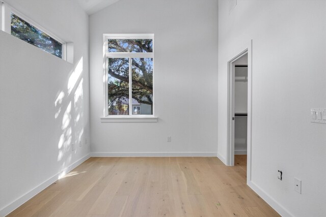 unfurnished room with light hardwood / wood-style floors and vaulted ceiling