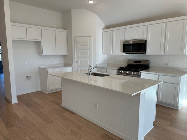222 Spirit St, Elgin, TX 78621 - kitchen with stainless steel appliances, vaulted ceiling, light wood-type flooring, and white cabinets