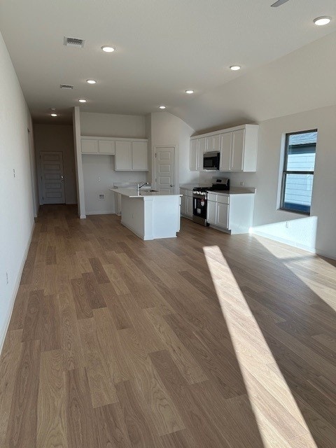 222 Spirit St, Elgin, TX 78621 - kitchen with appliances with stainless steel finishes, white cabinets, wood finished floors, recessed lighting, and an island with sink