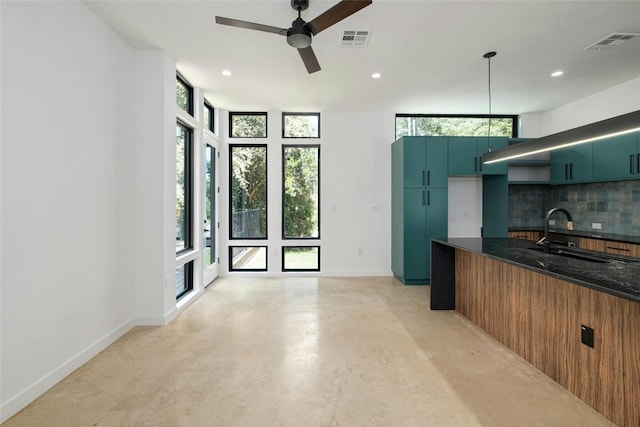 kitchen featuring sink, floor to ceiling windows, dark stone countertops, backsplash, and hanging light fixtures