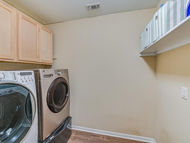 washroom featuring cabinets, washer and clothes dryer, and hardwood / wood-style flooring