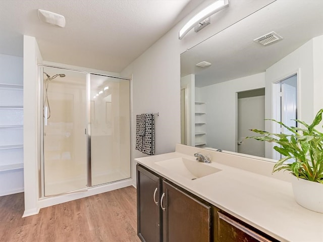 bathroom featuring walk in shower, wood-type flooring, and vanity