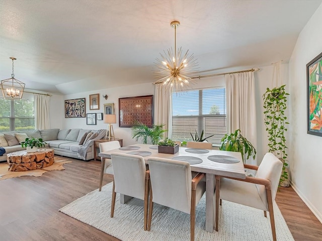 dining area with hardwood / wood-style flooring, a notable chandelier, and plenty of natural light