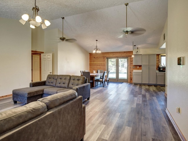 living room with ceiling fan with notable chandelier, high vaulted ceiling, hardwood / wood-style flooring, and a textured ceiling