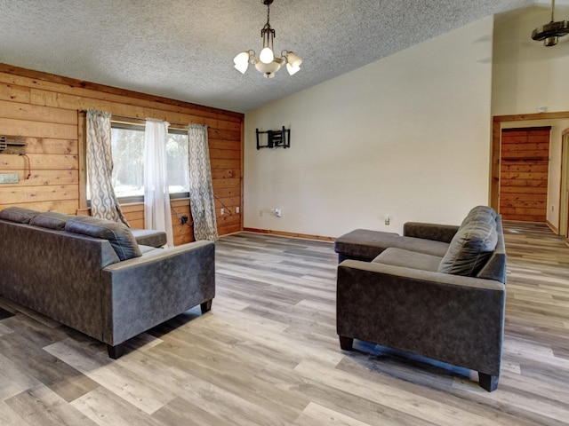 living room with wooden walls, hardwood / wood-style floors, a textured ceiling, and an inviting chandelier