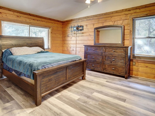 bedroom with wood walls, ceiling fan, light hardwood / wood-style floors, and lofted ceiling