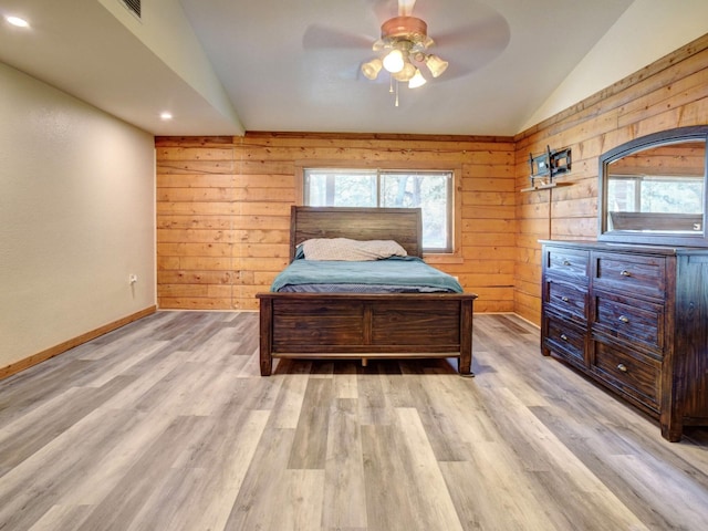 bedroom with wooden walls, ceiling fan, lofted ceiling, and light wood-type flooring