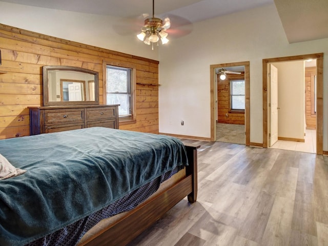 bedroom with vaulted ceiling, light hardwood / wood-style flooring, ensuite bath, and wood walls