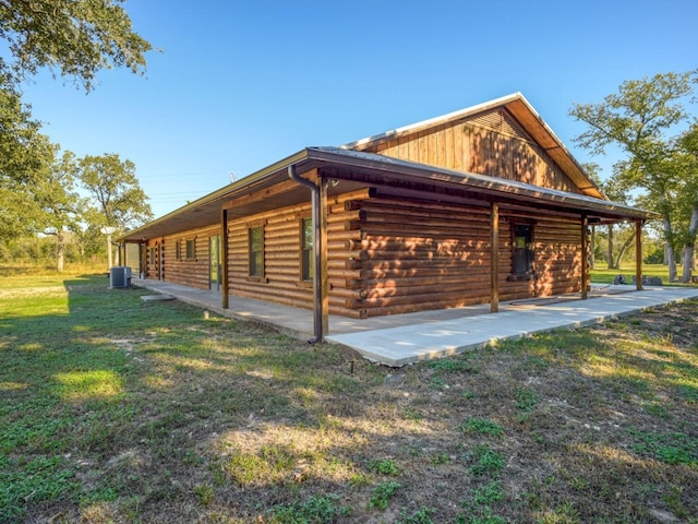 325 Simpson Ave, Cedar Creek, TX 78612 - view of side of home with log exterior, a patio, a yard, and central AC